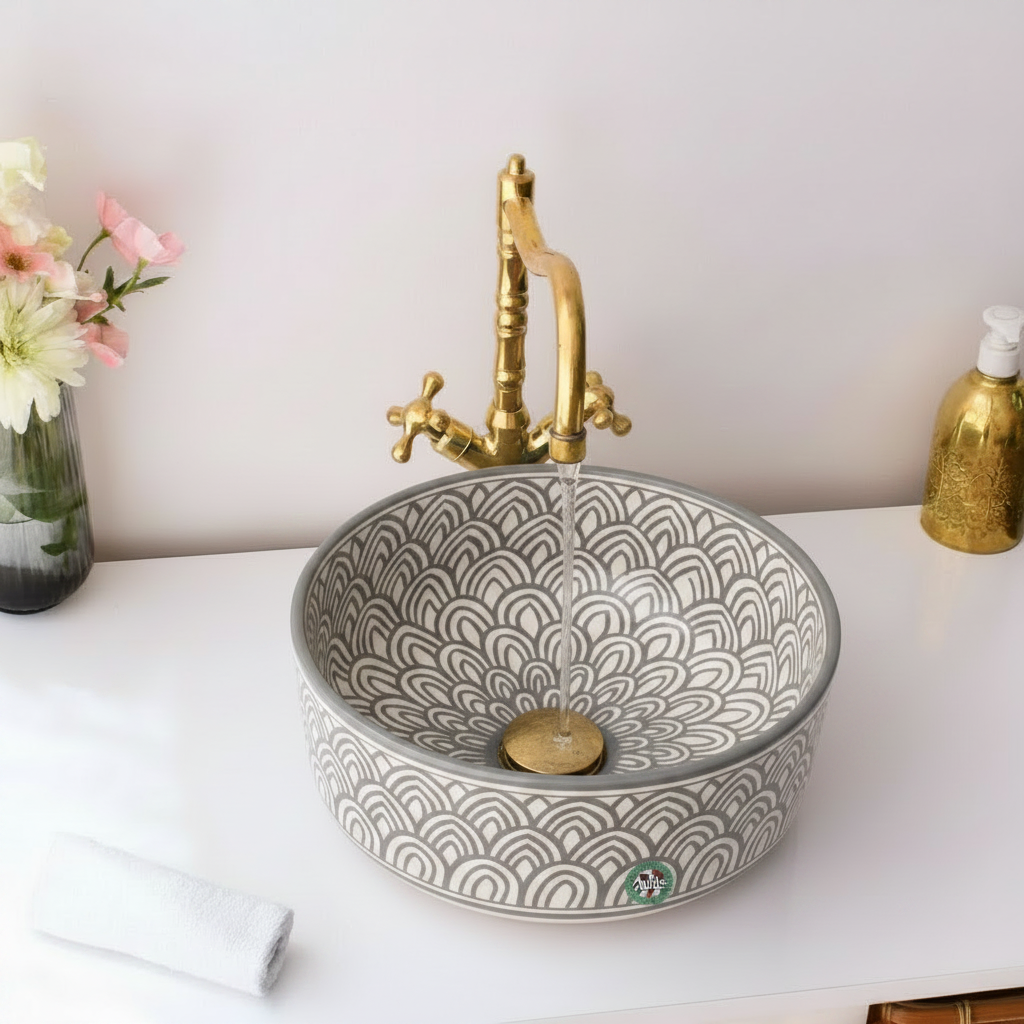 Gray patterned sink with gold faucet on a white surface